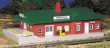 Bachmann Trains HO Scale Lighted Passenger Item # 46217. This is the Bachmann HO-Scale Lighted Sunnyvale Passenger Station Kit. Since 1947, hobbyists and collectors have made Plasticville U.S.A. products their structures of choice. Now, in addition to the traditional, easy-to-assemble kits, Bachmann is offering pre-assembled Plasticville U.S.A. buildings.
Plasticville pieces add character and dimension to your layout. Many buildings and accessories have been added to the Plasticville line throughout its history, and many are still produced from their original molds. As a fun challenge to collectors (you can even join the Plasticville Collectors Association), you can collect hundreds of product, color, and packaging variations that have occurred over the years. Whether you're new in town or an established civic leader, Bachmann builds Plasticville U.S.A. for you. City growth is limited only by your imagination!
Features:
Plastic styrene construction, for easy assembly.
Pre-wired, powered by power pack (not included).
No painting required.
Sunnyvale station has red clapboard siding, white windows and doors, a Green shingled roof, gray steps and platform.
Building houses a restaurant and ticket window.
A train schedule is posted on the outside of the building, along with an Uncle Sam's poster stating, "I Want You".
Includes a fork lift and driver.
Works with all HO scale electric trains.