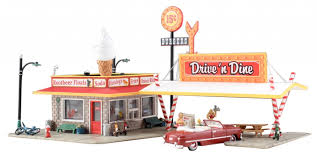 Woodland Scenics Drive 'n Dine - HO Scale Item # BR5029. Drive 'n Dine sets a nostalgic scene on any layout and features loads of details. Two carhops on skates deliver tasty treats, and a man in a bright red convertible waits for his order. Additional details include a vintage styled signage, soda straw supports for the awning, benches, picnic table, several bicycles, light poles and more! See photos for footprint.
This structure comes with pre-installed LED lighting made for use with the Just Plug® Lighting System. 20mA
RoHS Compliant
Colors may vary from actual product.