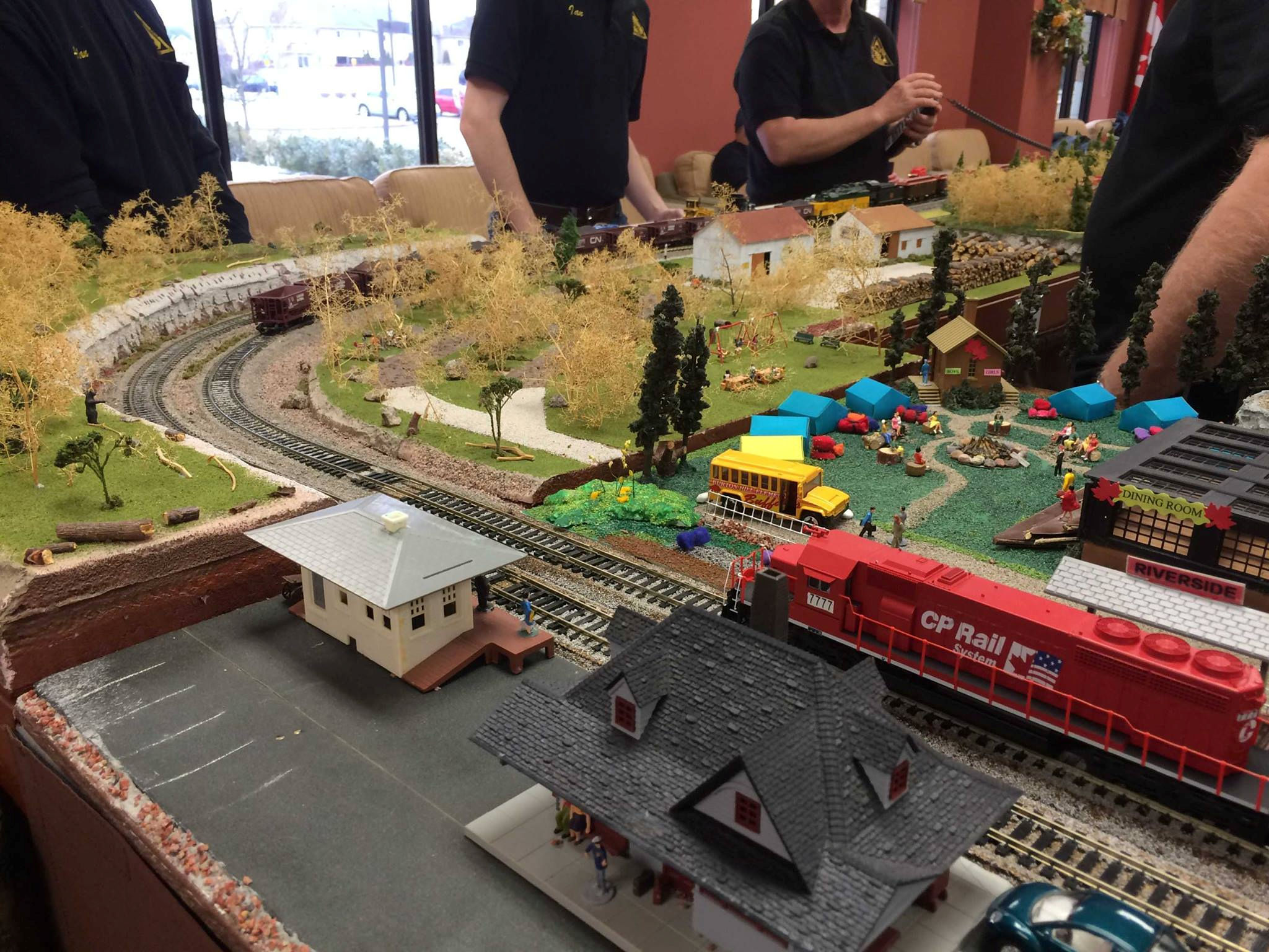 Model train layout with CP Rail locomotive, buildings, and campsite at Oshawa Pine Ridge Model Railroaders Club.