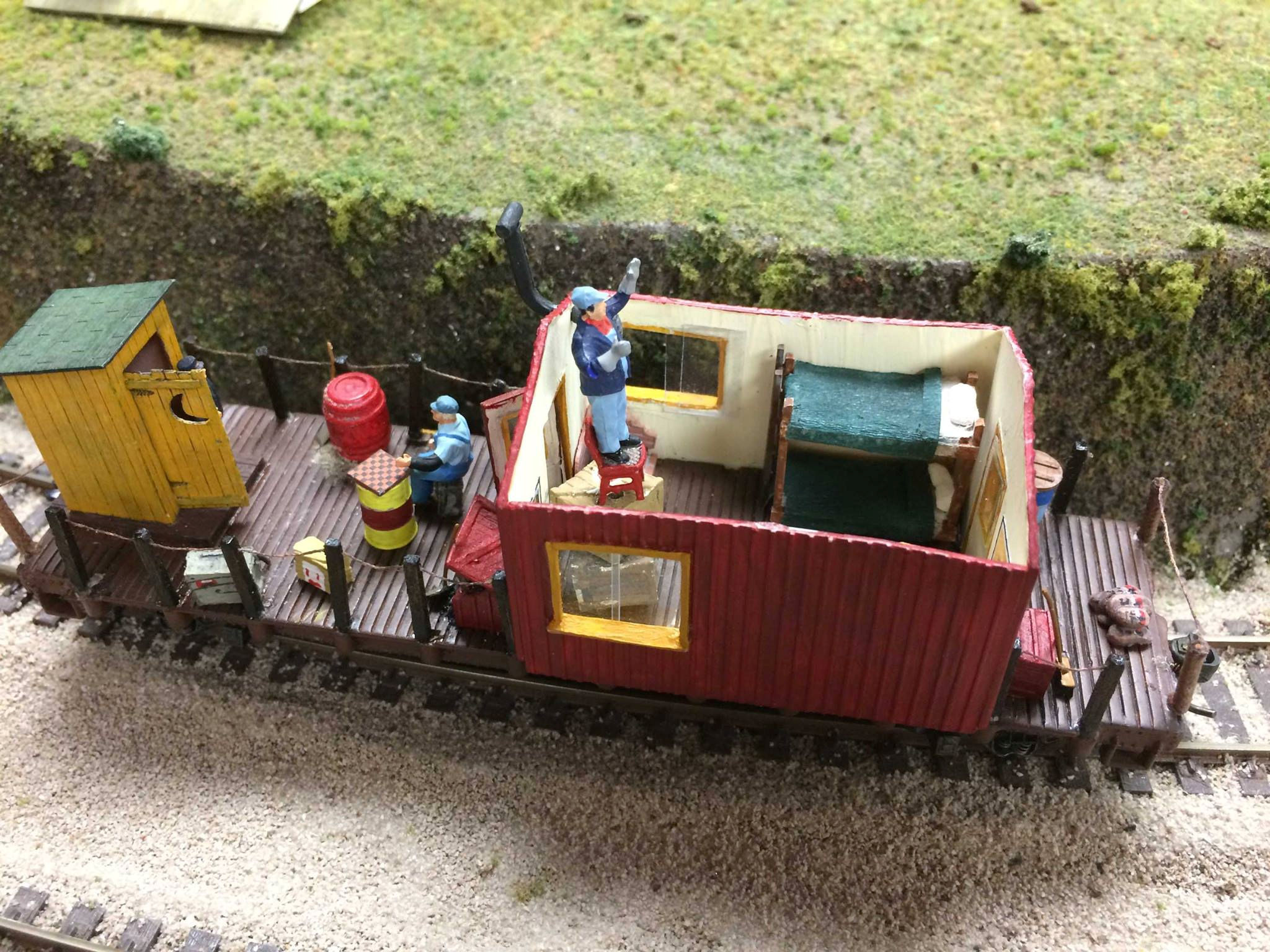 Model railroad work caboose with miniature crew, detailed interior, and work equipment at Oshawa Pine Ridge Model Railroaders Club.