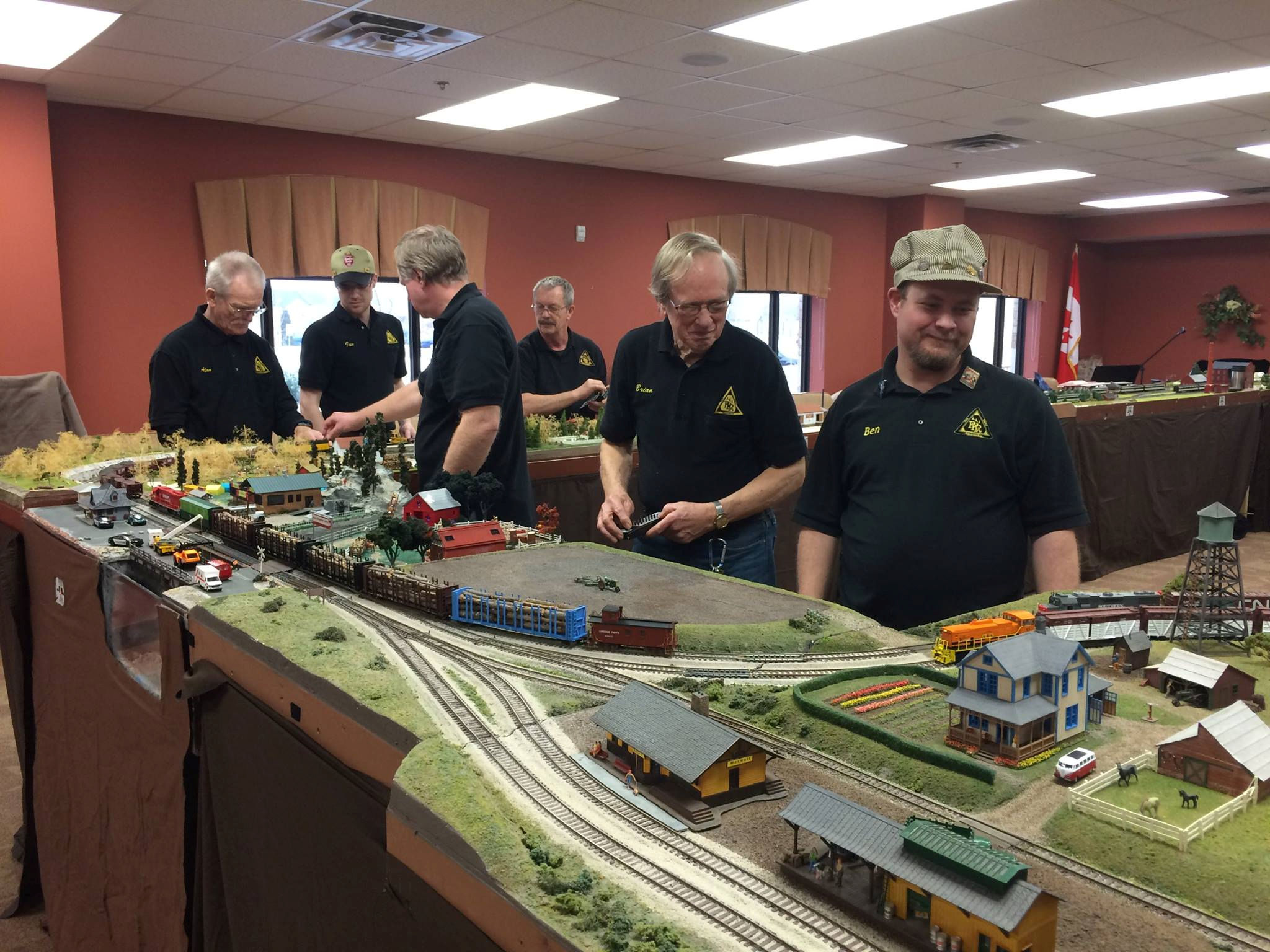 Oshawa Pine Ridge Model Railroaders Club members working on a detailed model train layout with intricate scenery and realistic structures.