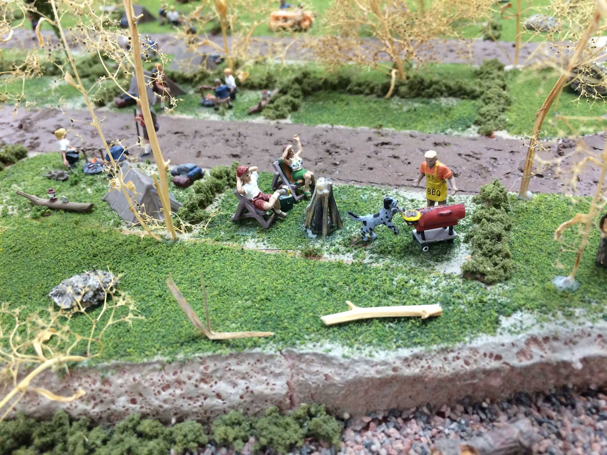 Miniature camping scene with people relaxing, grilling, and enjoying nature at the Oshawa Pine Ridge Model Railroaders Club.