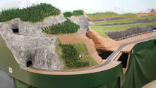 A scenic railway featuring a freight train crossing a steel truss bridge.