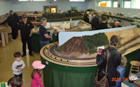 A countryside model railway scene featuring a train moving past farms.