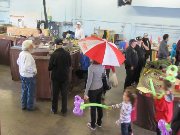 Crowd exploring model train displays at the Oshawa Pine Ridge Model Railroaders Club exhibition, featuring detailed railroad scenes.