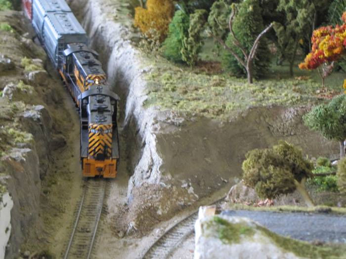 Model train running through a canyon with realistic rock formations and trees at the Oshawa Pine Ridge Model Railroaders Club.