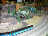 A model train depot with locomotives being serviced at a roundhouse.