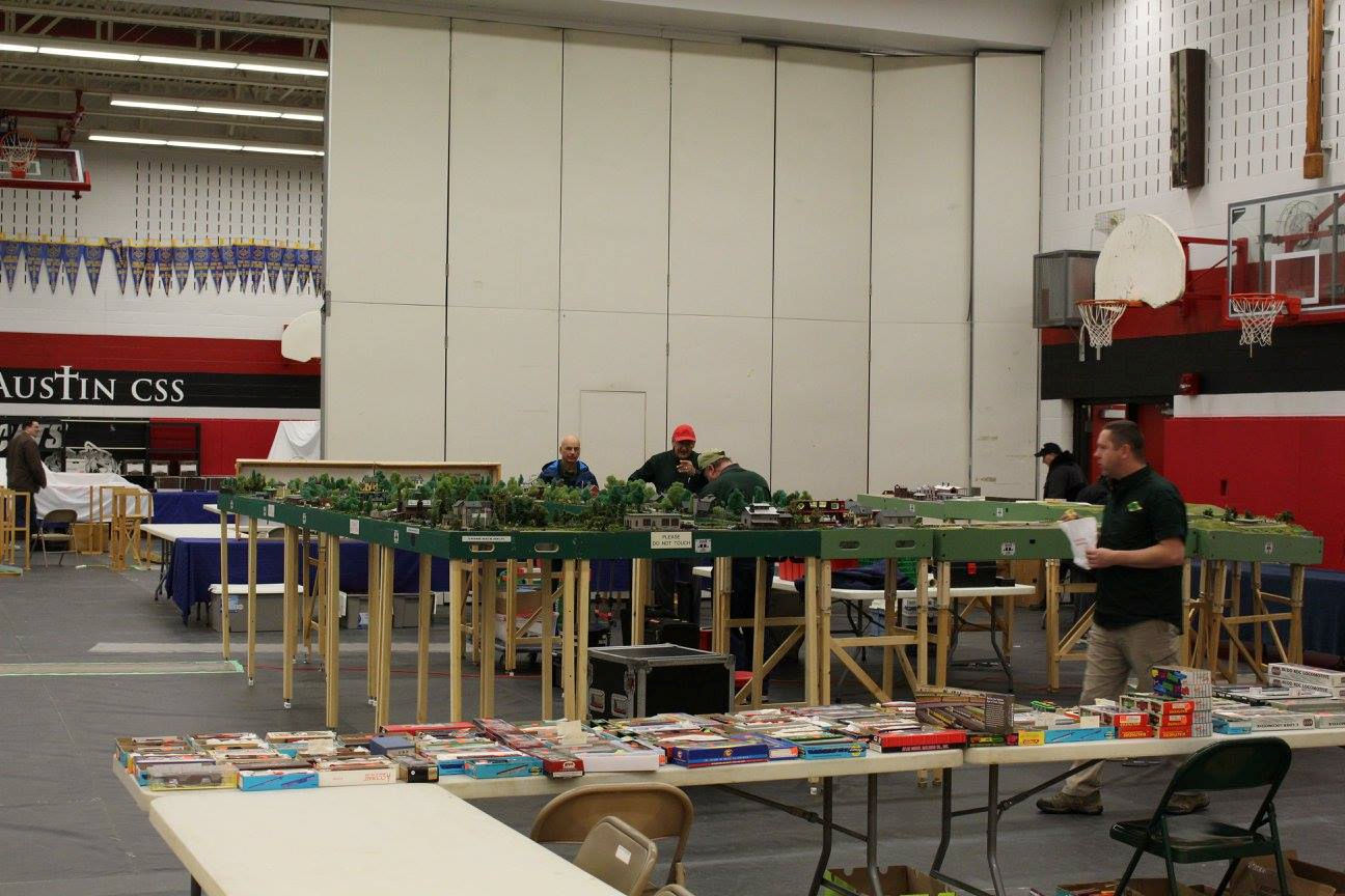 Large-scale model train display with detailed tracks and scenery at a model railroad event.