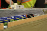 A model railway featuring a freight train crossing a steel bridge with realistic terrain.