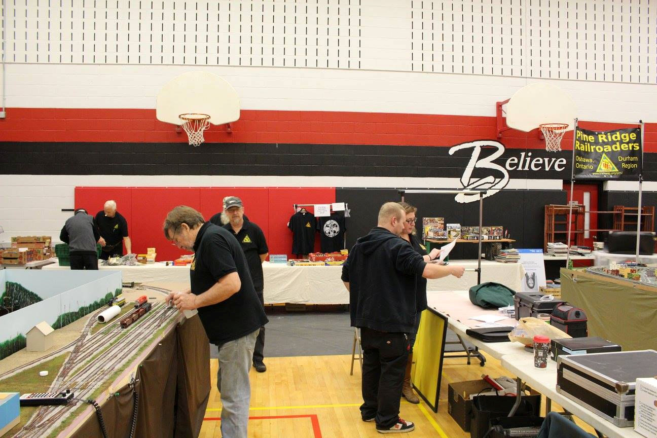 Pine Ridge Model Railroaders Club members preparing a model train layout and booth at an exhibition.