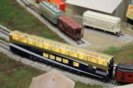 An industrial model train yard with freight cars, cargo containers, and cranes.