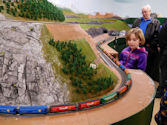 A passenger train pulling into a station with a waiting platform crowd.