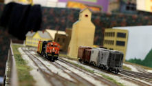 A historic railway scene featuring a vintage steam locomotive and period-accurate buildings.